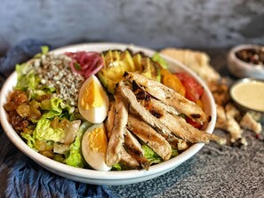 Een saladekom met gegrilde kip, sla en een gekookt ei.