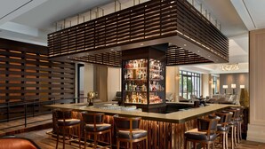 A modern bar area with a central island, bar stools, and a well-stocked liquor cabinet. - The Harpeth Franklin Downtown, Curio Collection by Hilton (Franklin)
