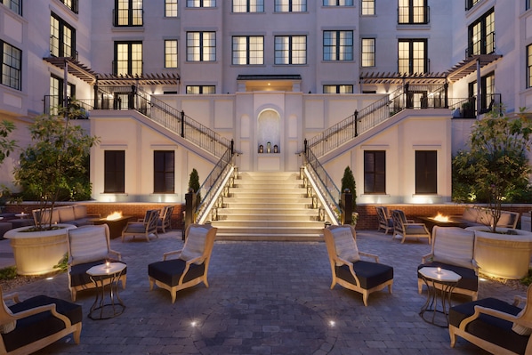 Un hotel con una escalera central, zona de estar al aire libre y varias ventanas.