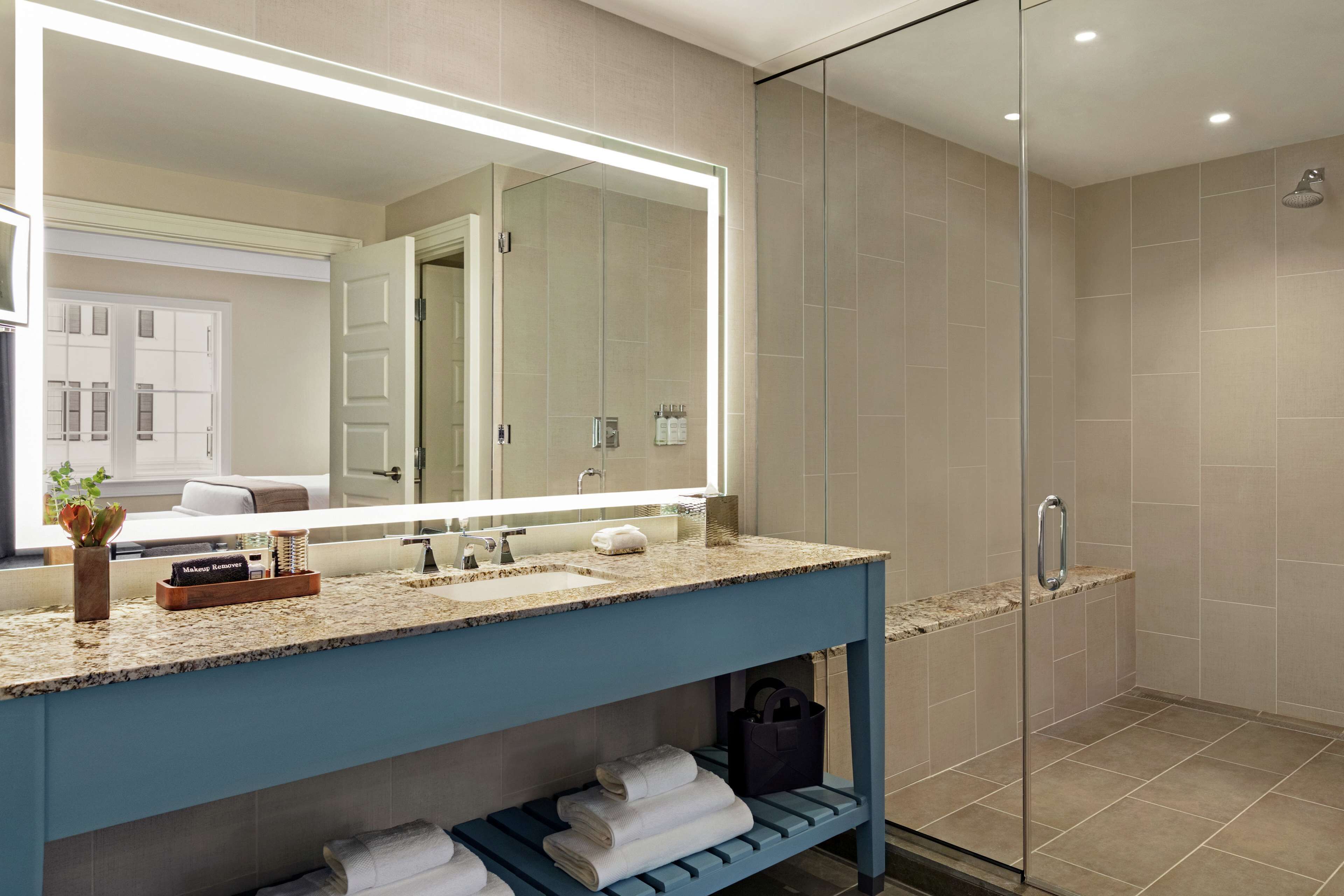 A modern bathroom with a large mirror, a sink, and a shower area.