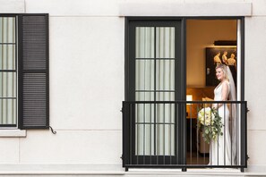 A balcony with a black railing, a window with vertical blinds, and a person holding a bouquet. - The Harpeth Franklin Downtown, Curio Collection by Hilton (Franklin)