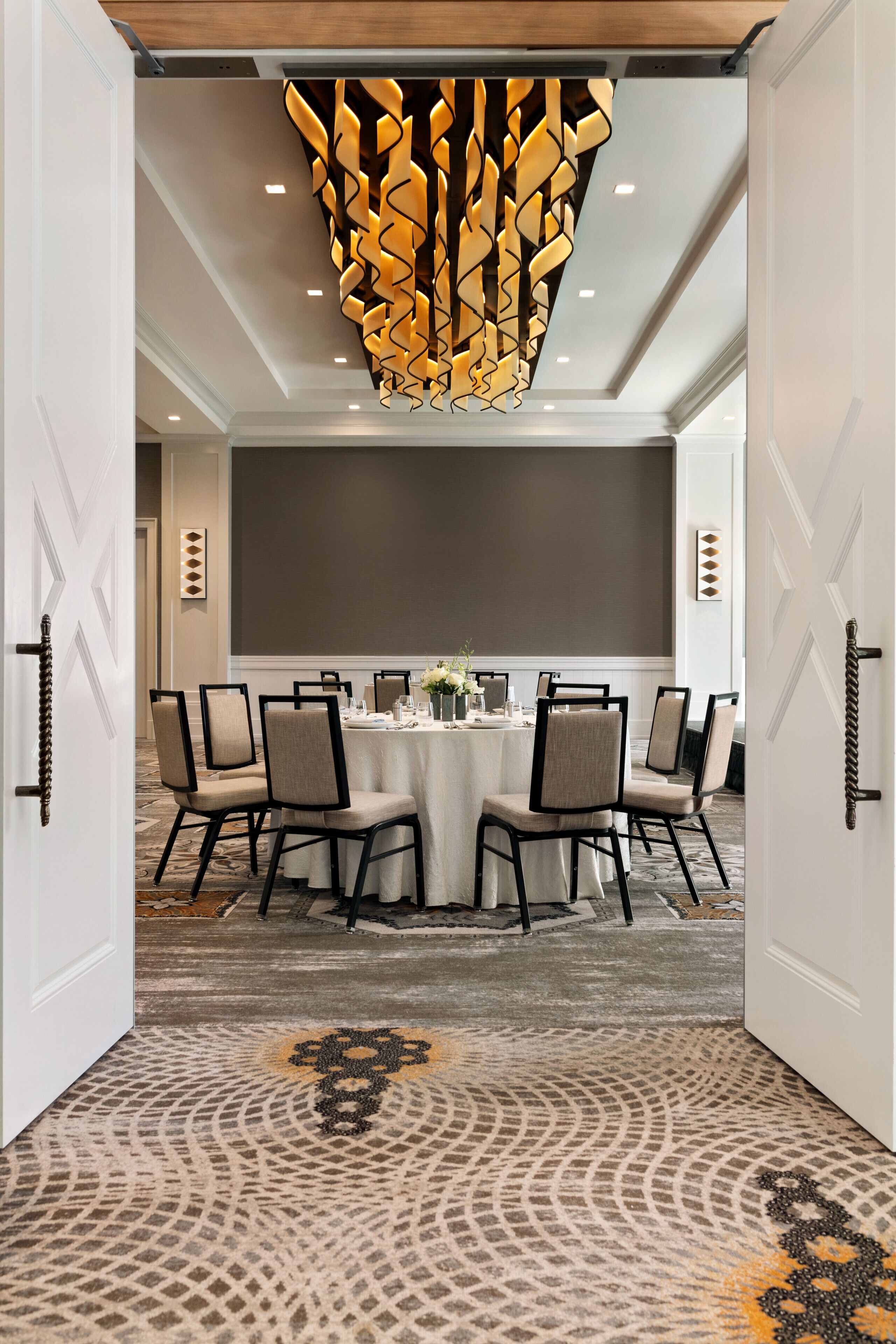 Une salle de conférence équipée d’une table ronde, de chaises et d’un luminaire décoratif au plafond.