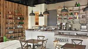 A modern kitchen with a central island, wooden shelves, and pendant lighting. - The Harpeth Franklin Downtown, Curio Collection by Hilton (Franklin)