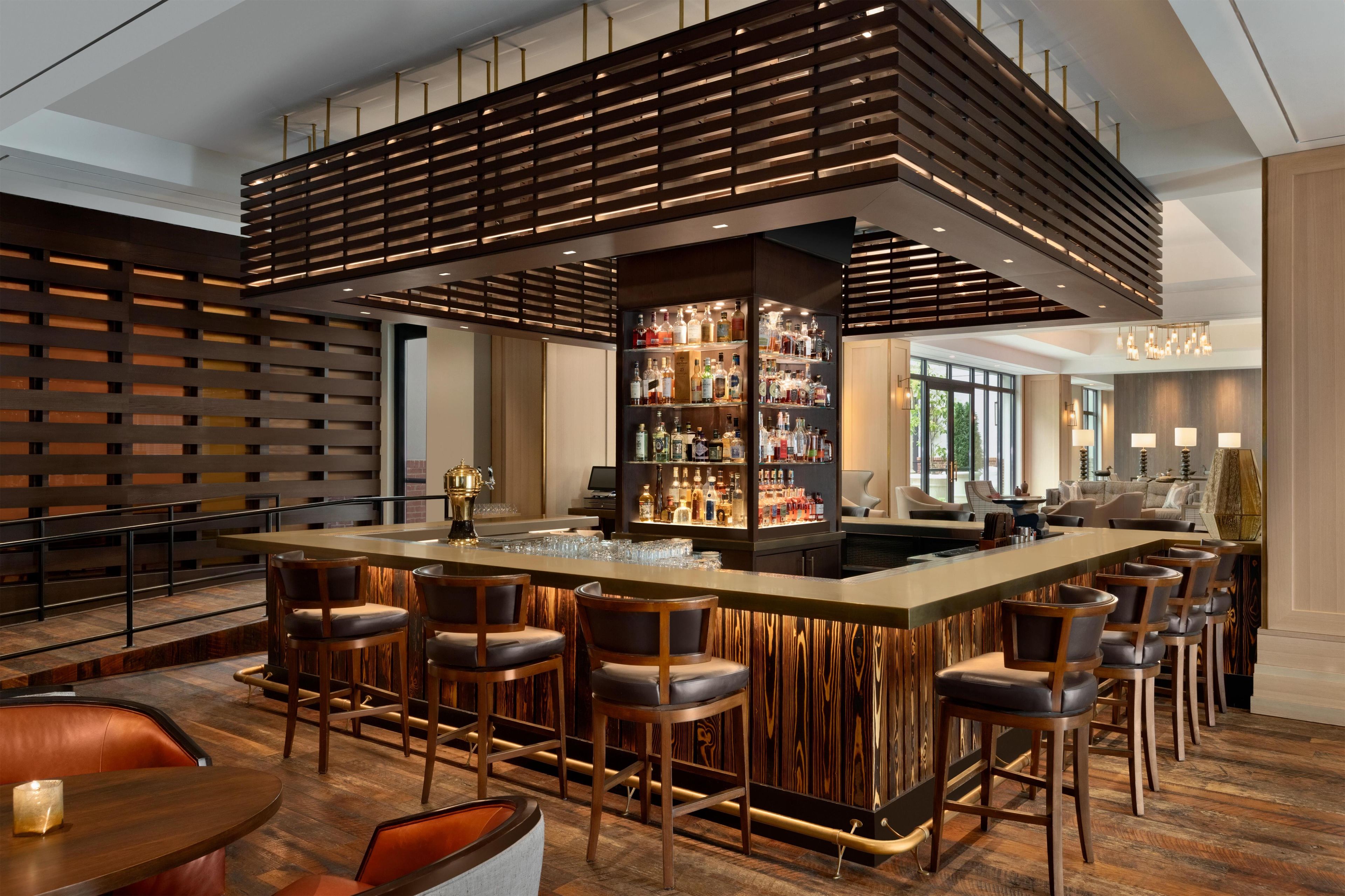 Eine moderne Bar mit einer zentralen Barinsel, Barhocker und einer Auswahl an Spirituosenflaschen.