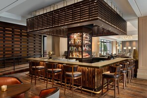 A modern bar area with a central island, bar stools, and a variety of liquor bottles.