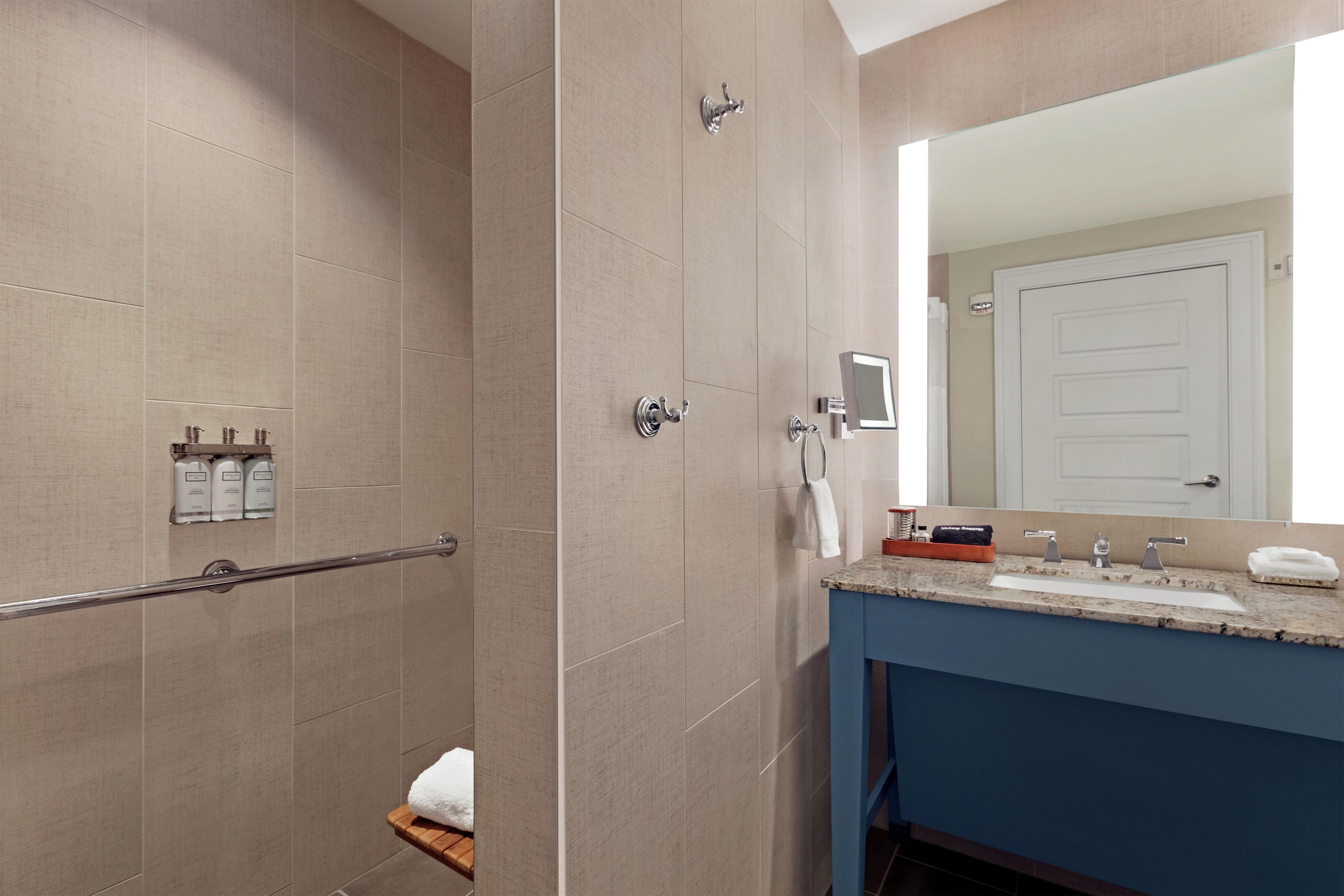 A modern bathroom with a shower, a vanity with a sink, and a large mirror.