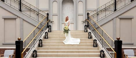 A bride on a grand staircase with a modern building in the background.