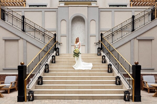 A bride on a grand staircase with a modern building in the background. - The Harpeth Franklin Downtown, Curio Collection by Hilton (Franklin)