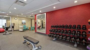 Een sportschool met een bank, gewichten en trainingsapparatuur.