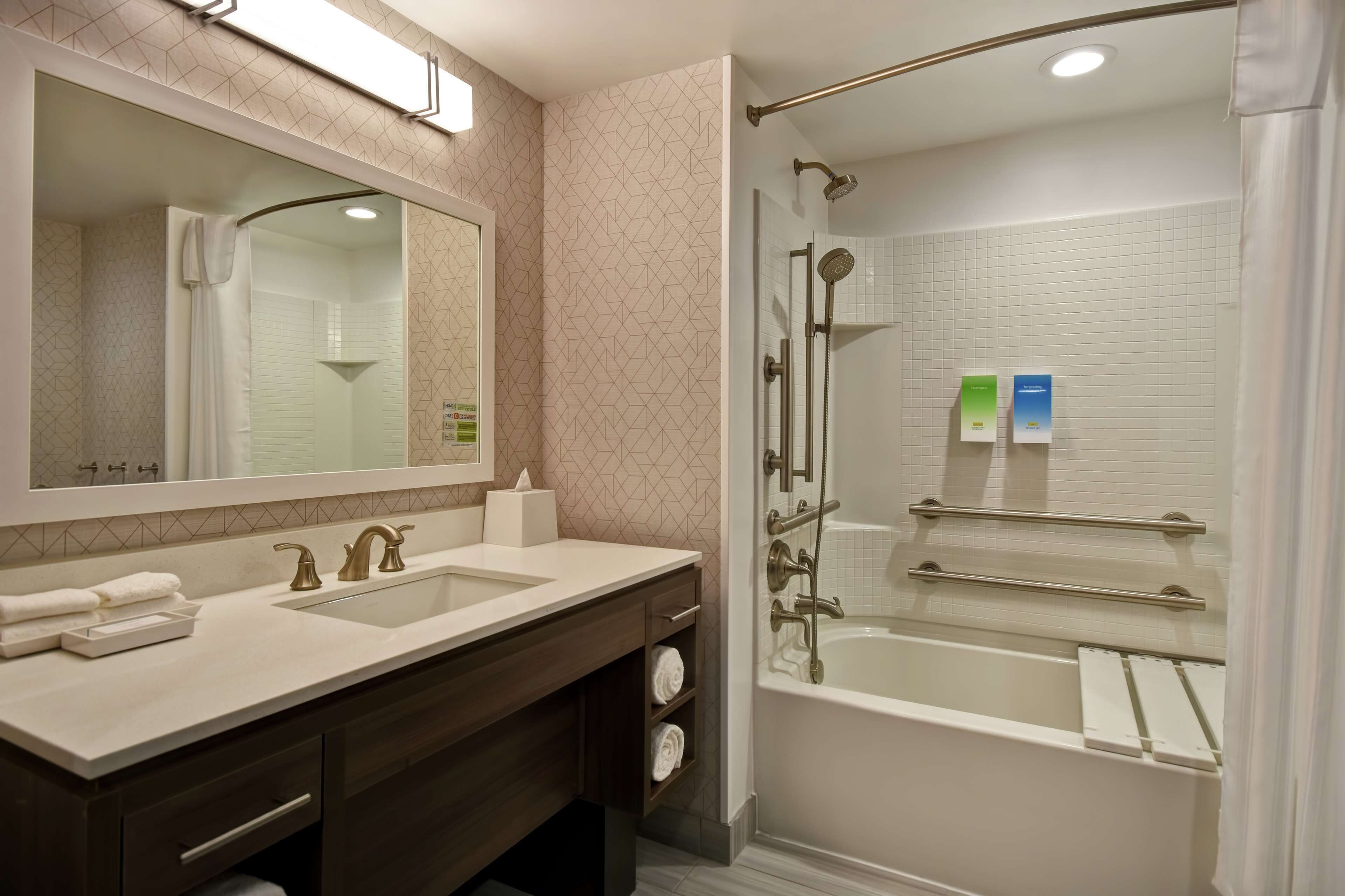 Un baño moderno con tocador de doble lavabo, un espejo grande, ducha con cerramiento de vidrio y bañera.