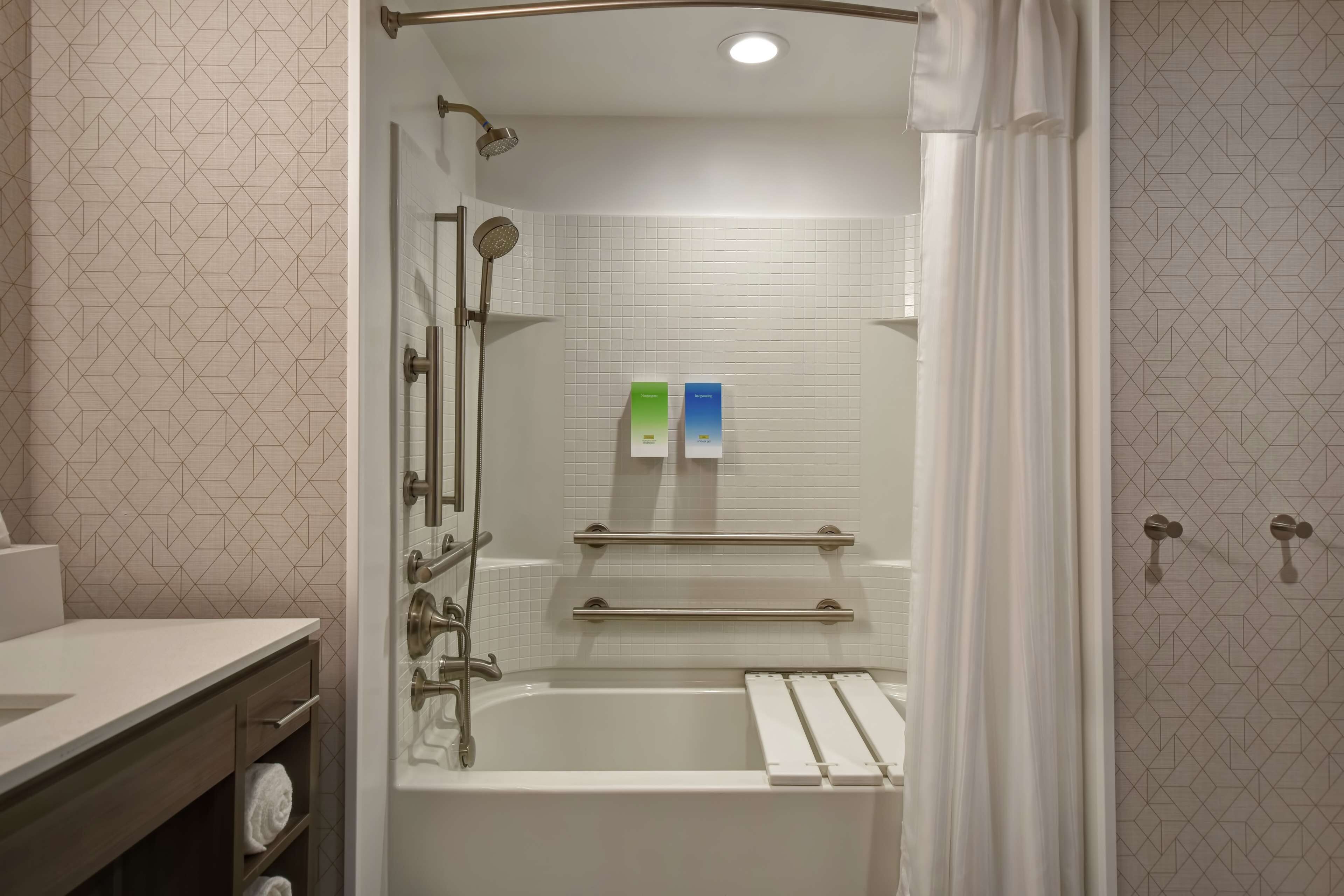 A modern bathroom with a bathtub, shower, and vanity.