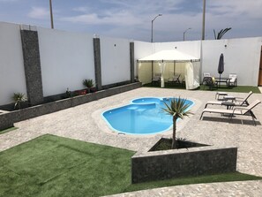 A backyard with a swimming pool, outdoor furniture, and a covered seating area. - New House by The Beach (Pisco)