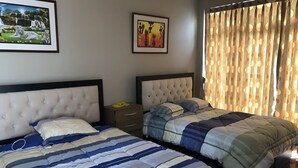 A hotel room with two beds, a nightstand, and two framed pictures on the wall. - New House by The Beach (Pisco)