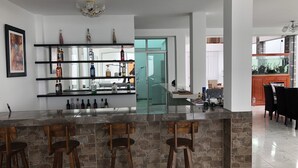 A modern kitchen with a bar area, stone walls, and a large window. - New House by The Beach (Pisco)