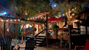 Eine Außenpatio-Terrasse mit Holzelementen, Lichterketten und einem Kamin.