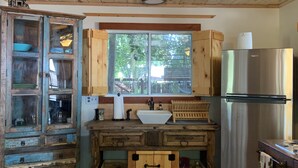 Eine rustikale Küche mit Holzausstattung, einem Edelstahlkühlschrank und einem Fenster mit Blick auf Grünflächen.