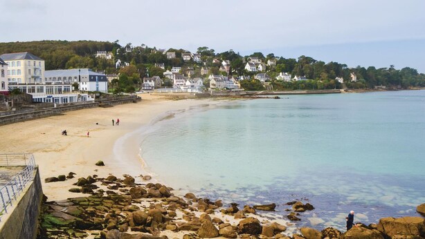 A coastal beach with a rocky shoreline, a promenade with buildings, and a clear view of the sea. - Cozy home in Plancoet with WiFi (Plancoet)