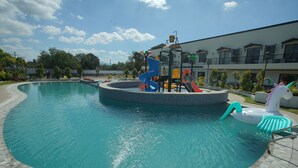A swimming pool with a water slide and inflatable unicorn float. - Segara Residencias (Olongapo)