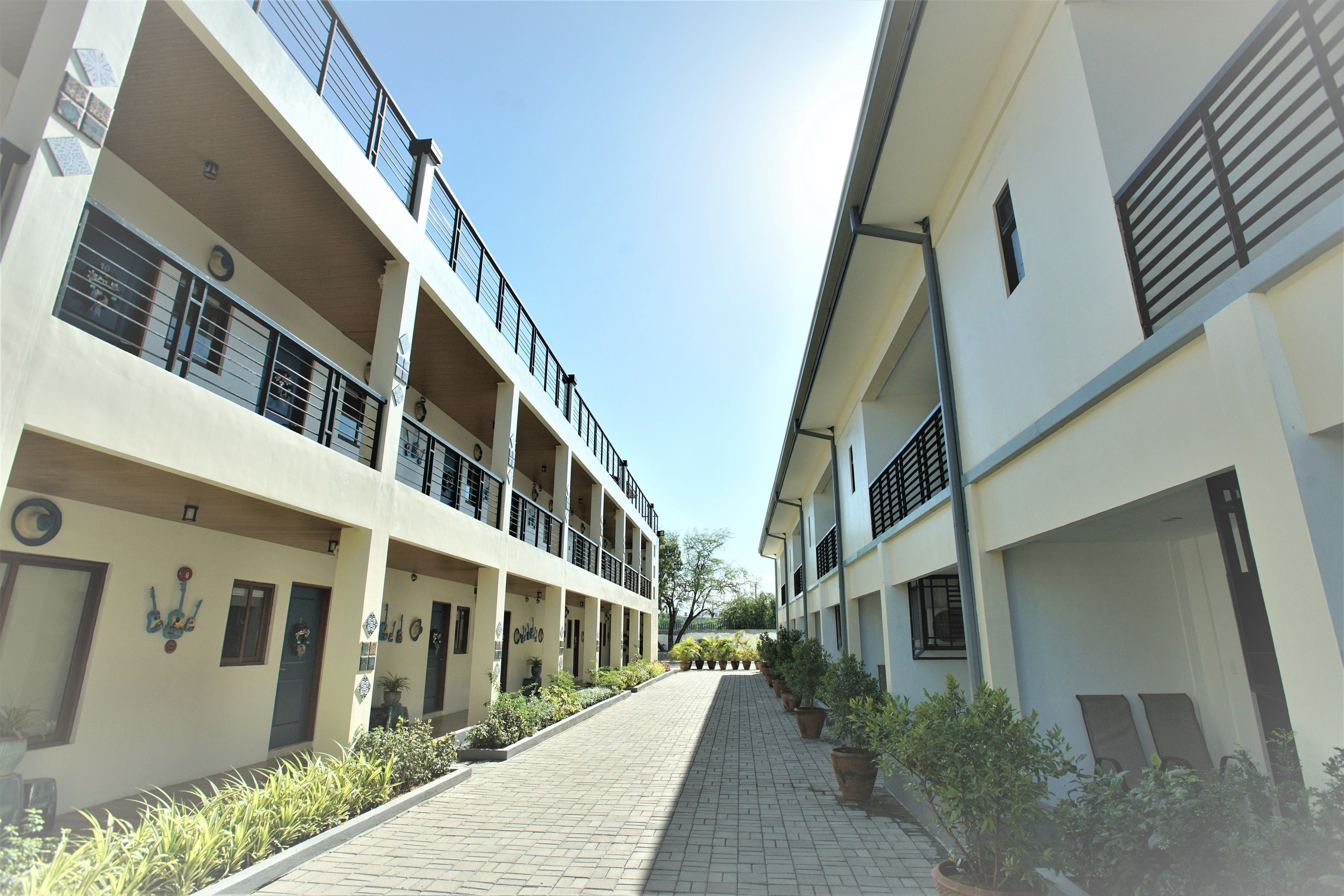 A multi-story building with balconies, potted plants, and a clear sky.