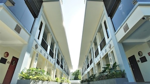 A symmetrical building with a central atrium, multiple windows, and potted plants. - Segara Residencias (Olongapo)