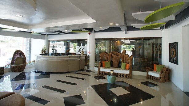 A modern lobby with a reception desk, seating area, and large windows. - Segara Residencias (Olongapo)