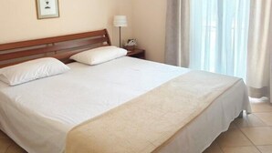 A hotel room with a large bed, a ceiling fan, a bedside table with a lamp, and a window with curtains. - Sunny Coco mat villa with a sea view,Cephalonia island (Kateleios)