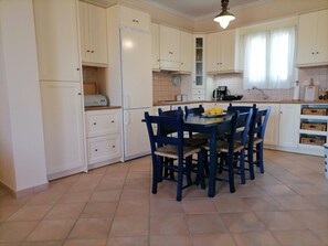 Kitchen features a central island with sink and stove, along with ample storage and a refrigerator.