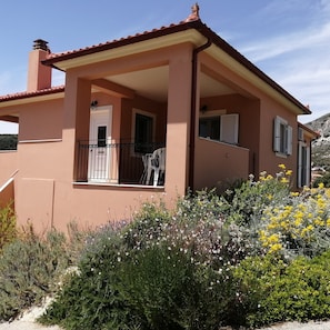Enjoy the serene views from the balcony with a flat roof, surrounded by lush vegetation and a red-tiled roof.