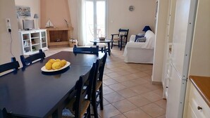 A dining area with a table set for four, a white sofa, and a small side table. - Sunny Coco mat villa with a sea view,Cephalonia island (Kateleios)