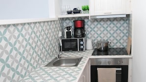Una cocina compacta con salpicadero estampado, microondas, cafetera y horno pequeño.