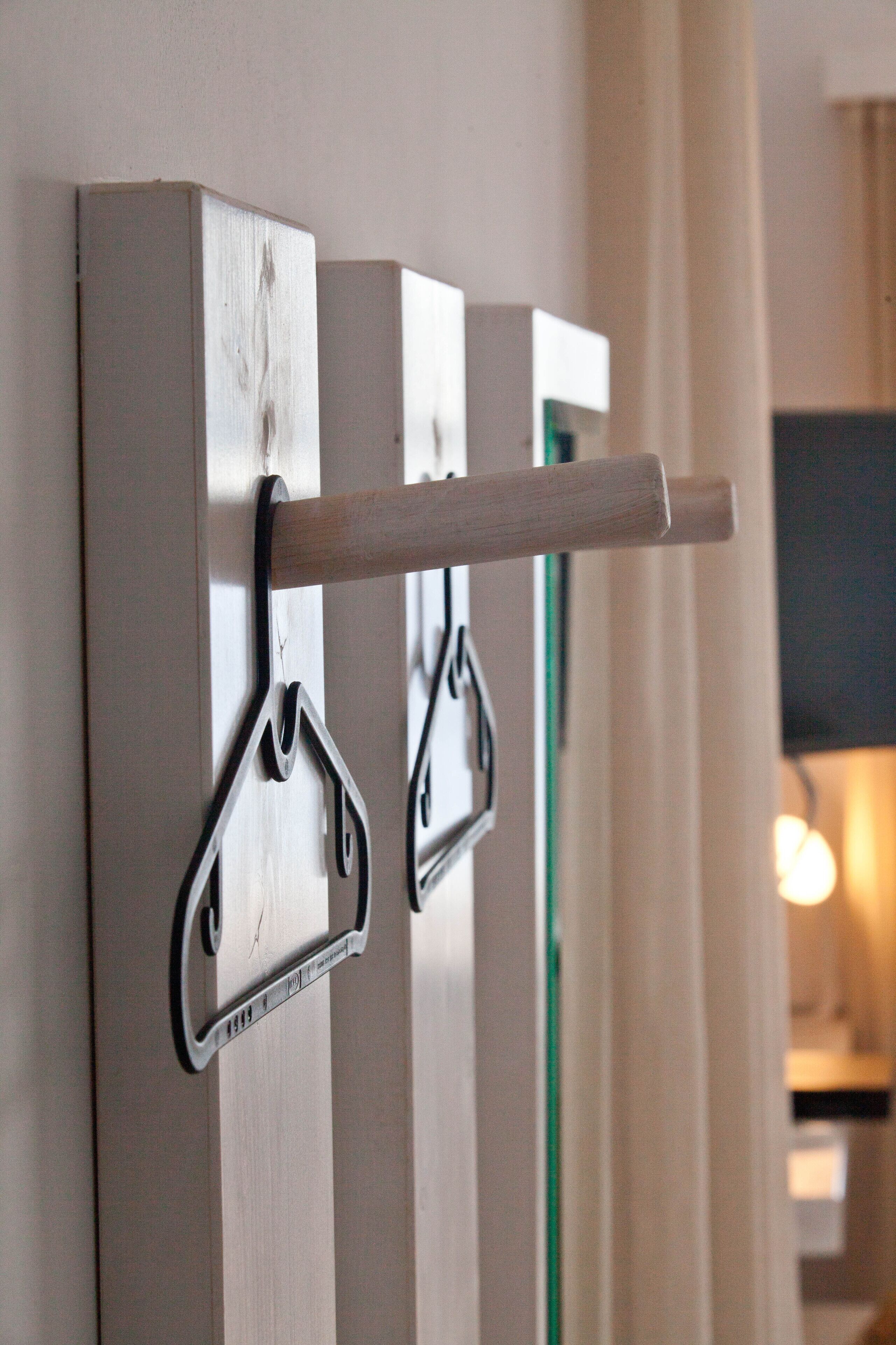 A wall-mounted coat rack with a wooden handle and metal hooks.