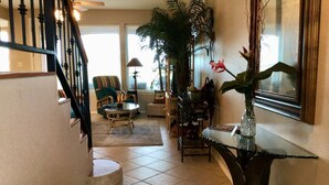 A spacious living area with a staircase, a dining table, and a large potted plant. - Half Moon Harbor- 15 HT (Laguna Vista)