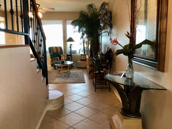 A spacious living area with a staircase, a dining table, and a large potted plant.