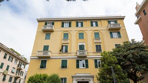 A multi-story yellow building with balconies, a central entrance, and surrounding greenery. - Casa Azzurra by Wonderful Italy (Genova)
