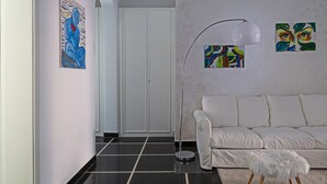 A modern living room with a white sofa, a fluffy white stool, and abstract paintings on the walls. - Casa Azzurra by Wonderful Italy (Genova)