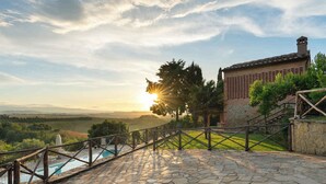 A stone staircase leading to a pool with a view of a sunset over rolling hills. - Villa with private pool and air conditioning (Villamagna)