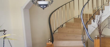 Eine Treppe mit hölzernem Geländer und einem roten, gemusterten Teppich.