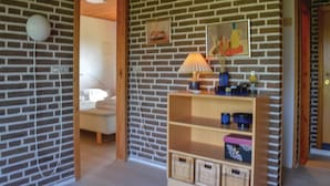 A room with a brick wall, a wooden shelf with baskets, and a bed with a white headboard. - Beach front home in Sæby with WiFi (Sæby)