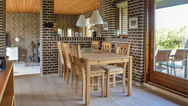 A spacious dining area with a brick wall, wooden ceiling, and large windows. - Beach front home in Sæby with WiFi (Sæby)