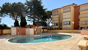 A swimming pool with tiled flooring, a small covered area, and a building with balconies in the background. - Cosy Studio w/ Mezzanine, Parking & Pools - 400m from Beach (Argelès-sur-Mer)