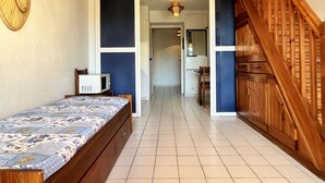 A bedroom with a bed, a television, and a wooden staircase. - Cosy Studio w/ Mezzanine, Parking & Pools - 400m from Beach (Argelès-sur-Mer)