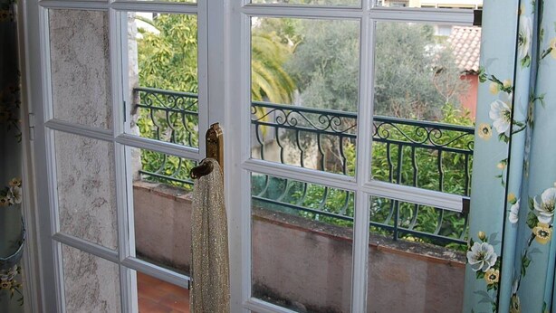 Une fenêtre donnant sur un balcon et des immeubles.