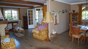 Un salon chaleureux avec des poutres apparentes, un canapé, une table et un coin repas.
