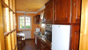 Une cuisine avec des meubles de rangement en bois, un réfrigérateur, un four et une table à manger avec des chaises.