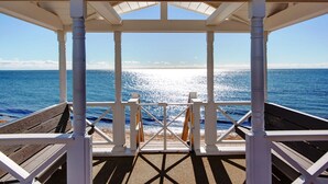 A covered wooden deck with a view of the ocean. - The Ultimate Nantucket Sound Beachfront Oasis! (2144) (Dennis Port)