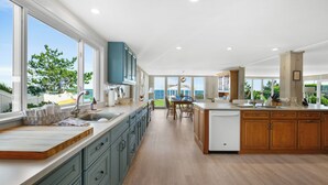 A spacious kitchen with a large island, wooden cabinets, and a view of the outdoors. - The Ultimate Nantucket Sound Beachfront Oasis! (2144) (Dennis Port)