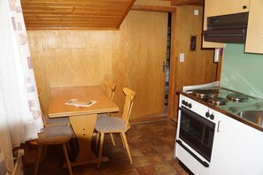 Compact kitchen area with a table and chairs, featuring a stove with burners and oven.