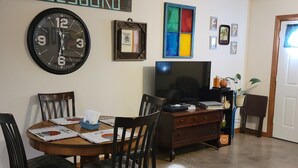 A dining area with a wooden table, chairs, and a clock on the wall.