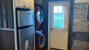 Een praktische keuken met een ingebouwde wasmachine en droger, een roestvrijstalen spoelbak en een houten aanrecht.