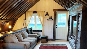 Een gezellig slaapkamer onder de dakpannen met een slaapbank, een bed en uitzicht.